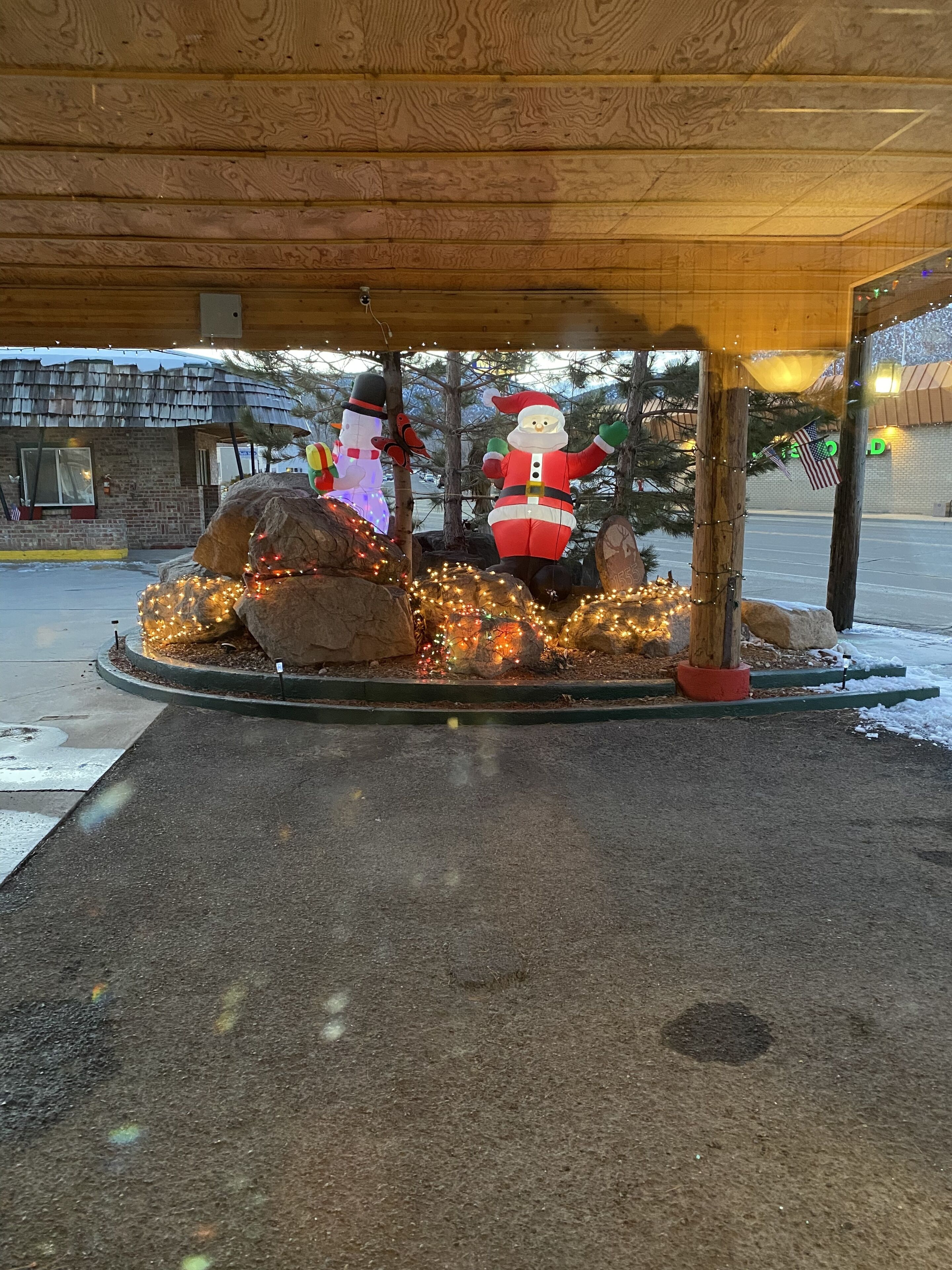 Un espace extérieur aménagé et décoré, doté d’une structure en bois, et agrémenté de figurines représentant un bonhomme de neige et le Père Noël.