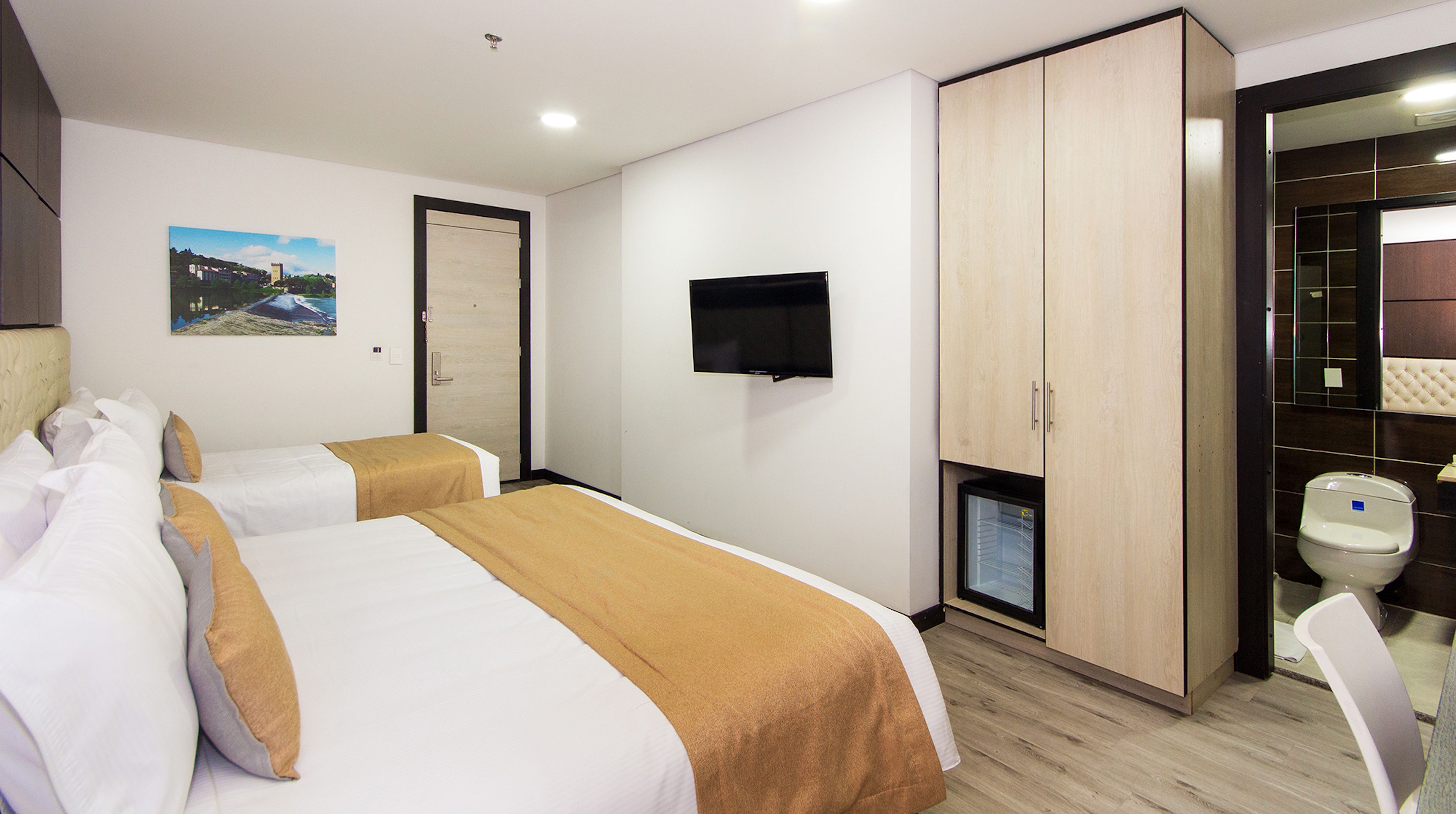 Een hotelkamer met twee bedden, een televisie, een kast en een kleine badkamer.