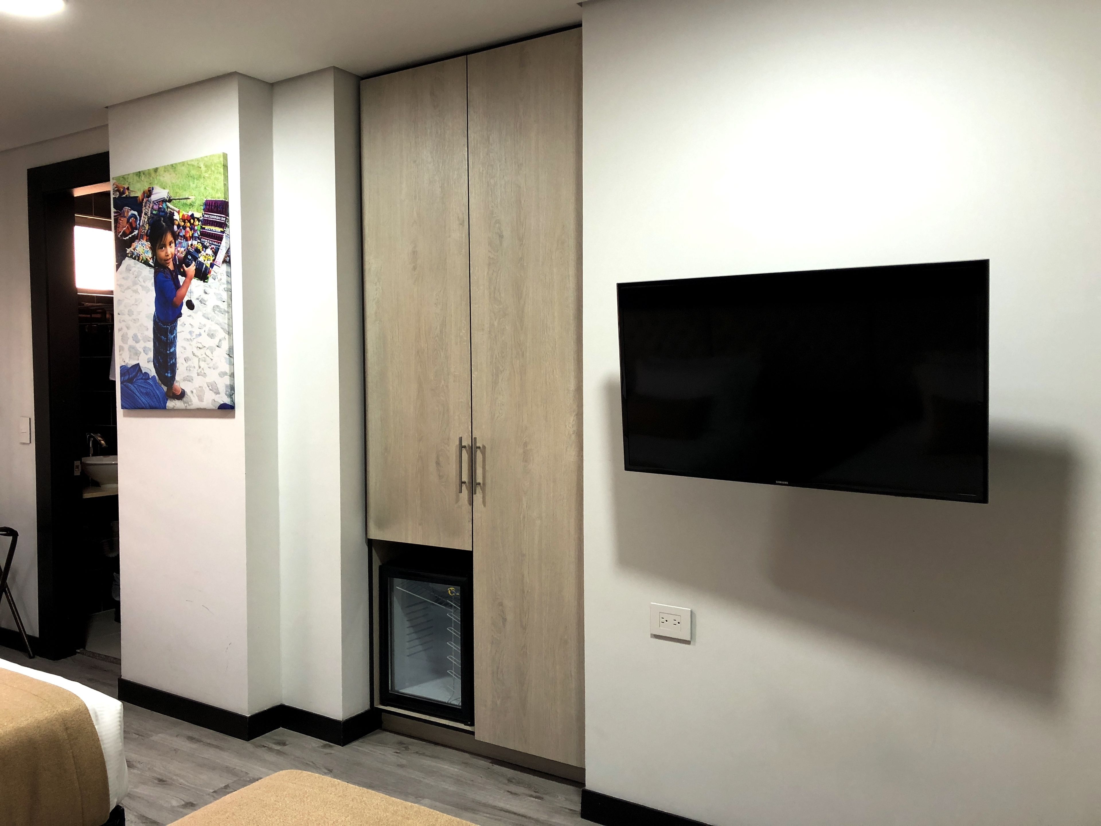 Una habitación con un armario, un televisor montado en la pared y un cartel en la pared.