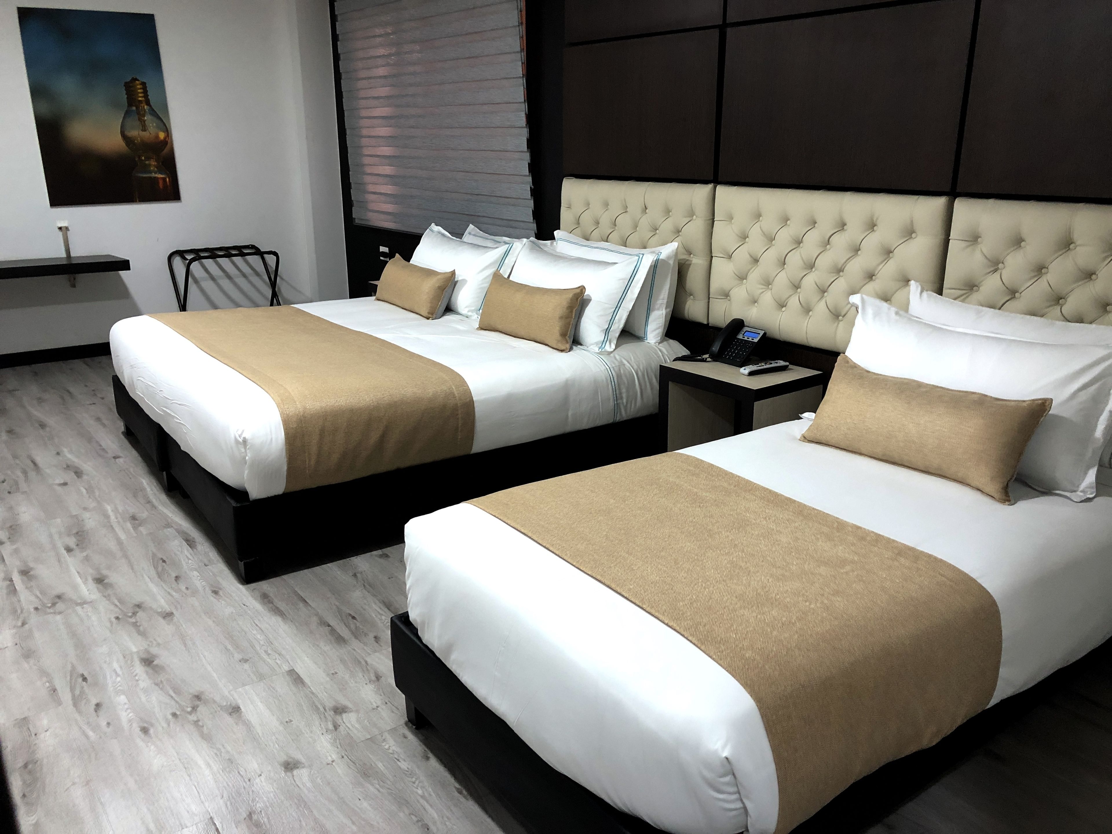 Ein Hotelzimmer mit zwei Betten, einem Nachttisch mit Telefon und einer Wandleuchte.