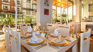 A dining area with tables set for four, featuring gold-rimmed plates and white napkins.