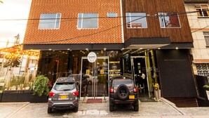 A multi-story building with a mix of brick and wood panel facades, large windows, and a visible entrance with a car parked outside.