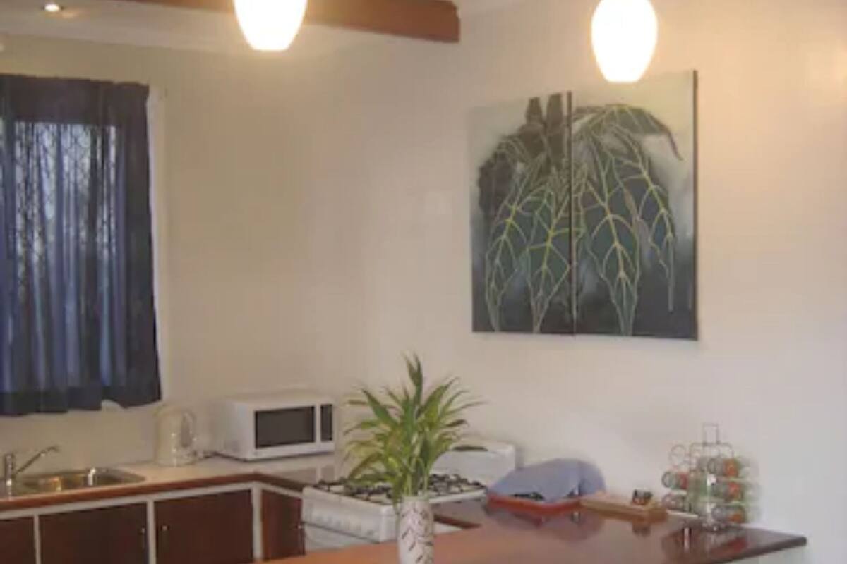 A kitchen with a central island, bar stools, a microwave, and a potted plant.