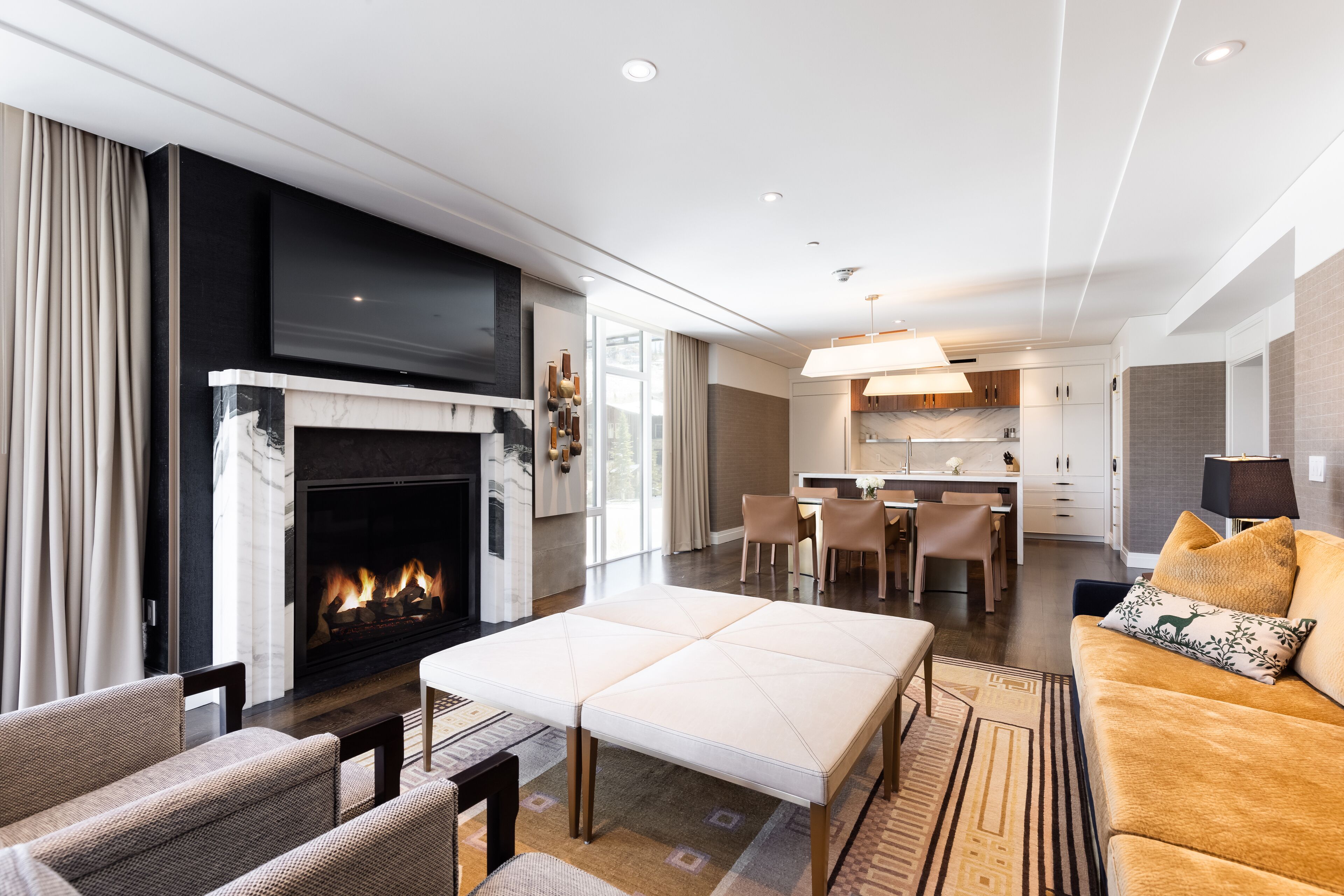 A modern living room with a fireplace, a dining area, and a kitchen.