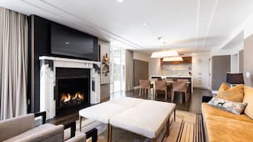 A modern living room with a fireplace, a dining area, and a kitchen.