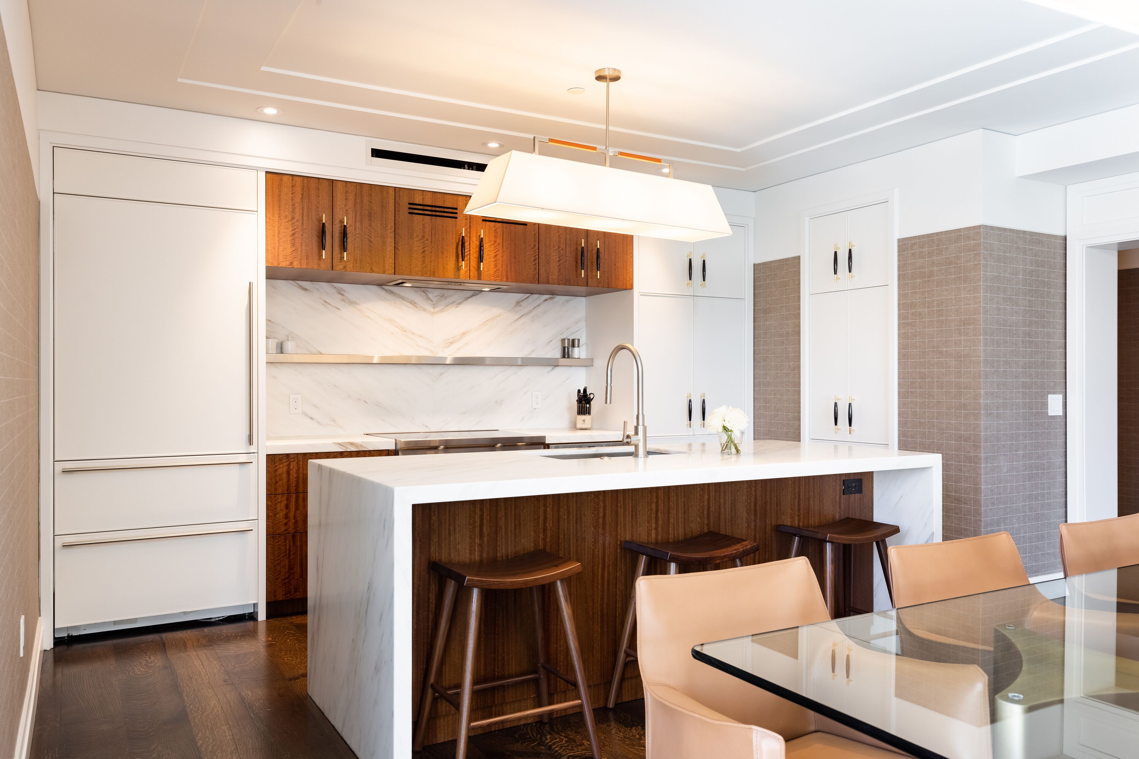Una cocina moderna con una isla central, armarios de madera y un salpicadero de mármol.