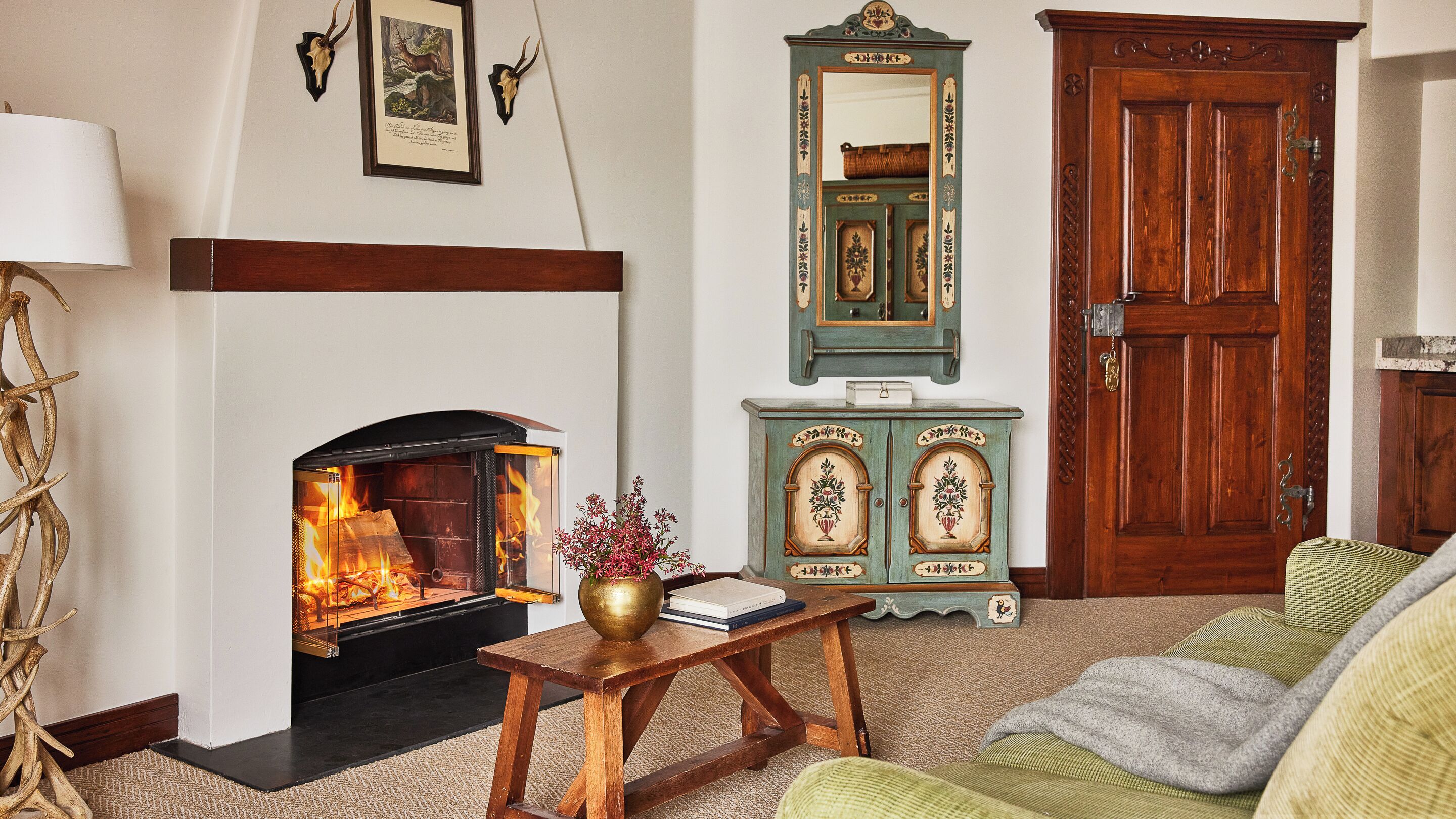 A cozy living room with a fireplace, a wooden cabinet, and a green door.