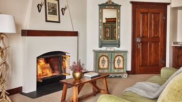 A cozy living room with a fireplace, a wooden cabinet, and a green door.