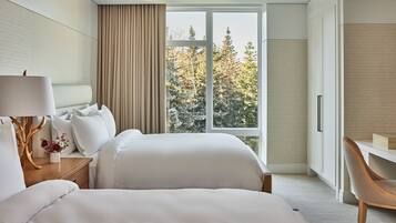 A hotel room with a large bed, a desk, and a view of trees through the window.
