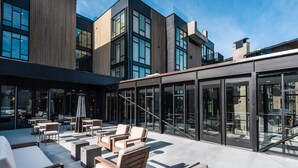 A modern building with large windows and a patio area with outdoor seating. - Goldener Hirsch, Auberge Collection (Park City)