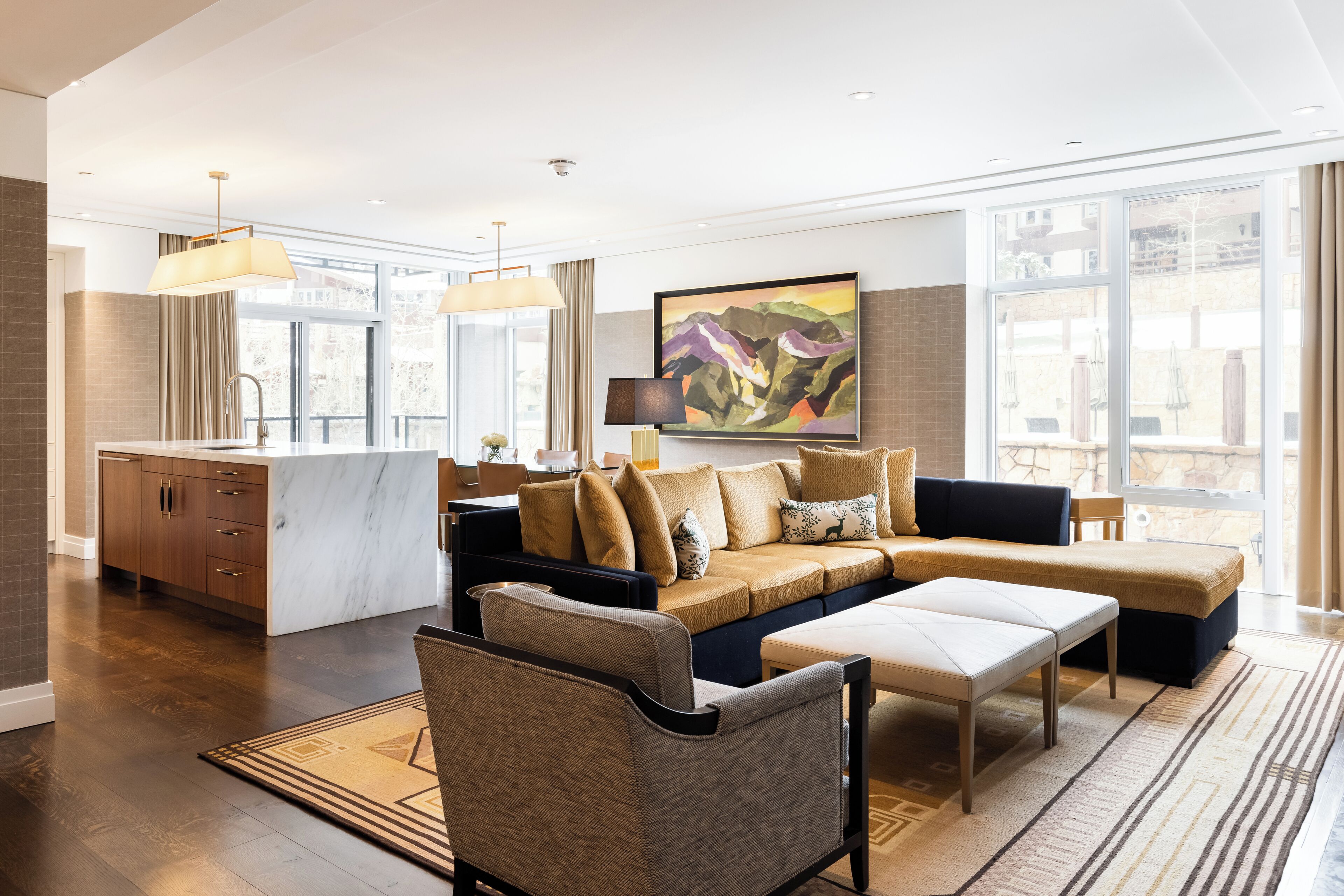 A spacious living area with a sofa, ottoman, and a dining area with a kitchen counter.
