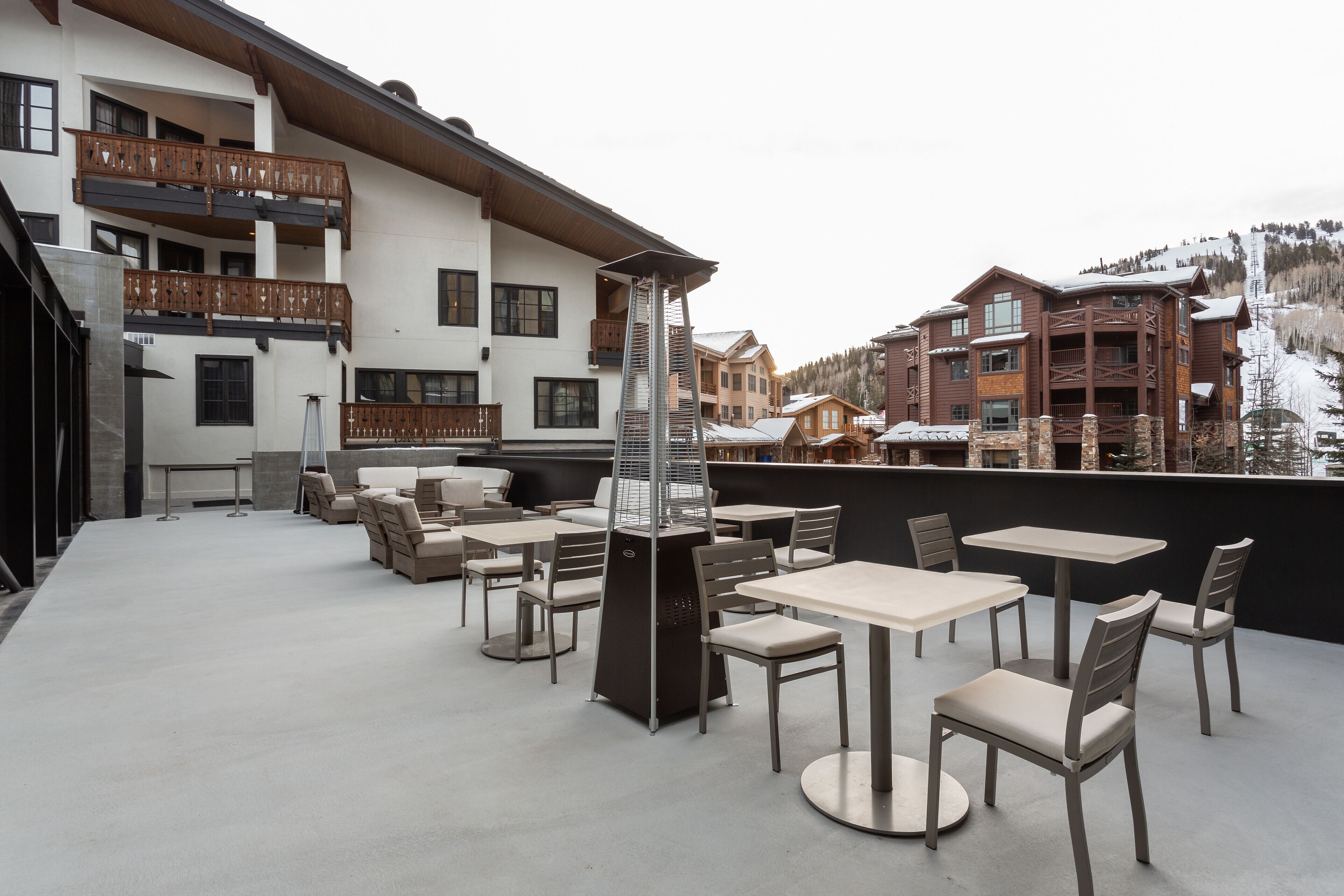An outdoor patio with tables and chairs, a fireplace, and a view of surrounding buildings.