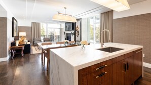 A modern kitchen with a marble island, wooden cabinets, and pendant lighting. - Goldener Hirsch, Auberge Collection (Park City)