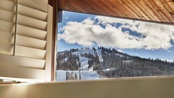 A window view of a snowy mountain landscape with trees and a clear sky.