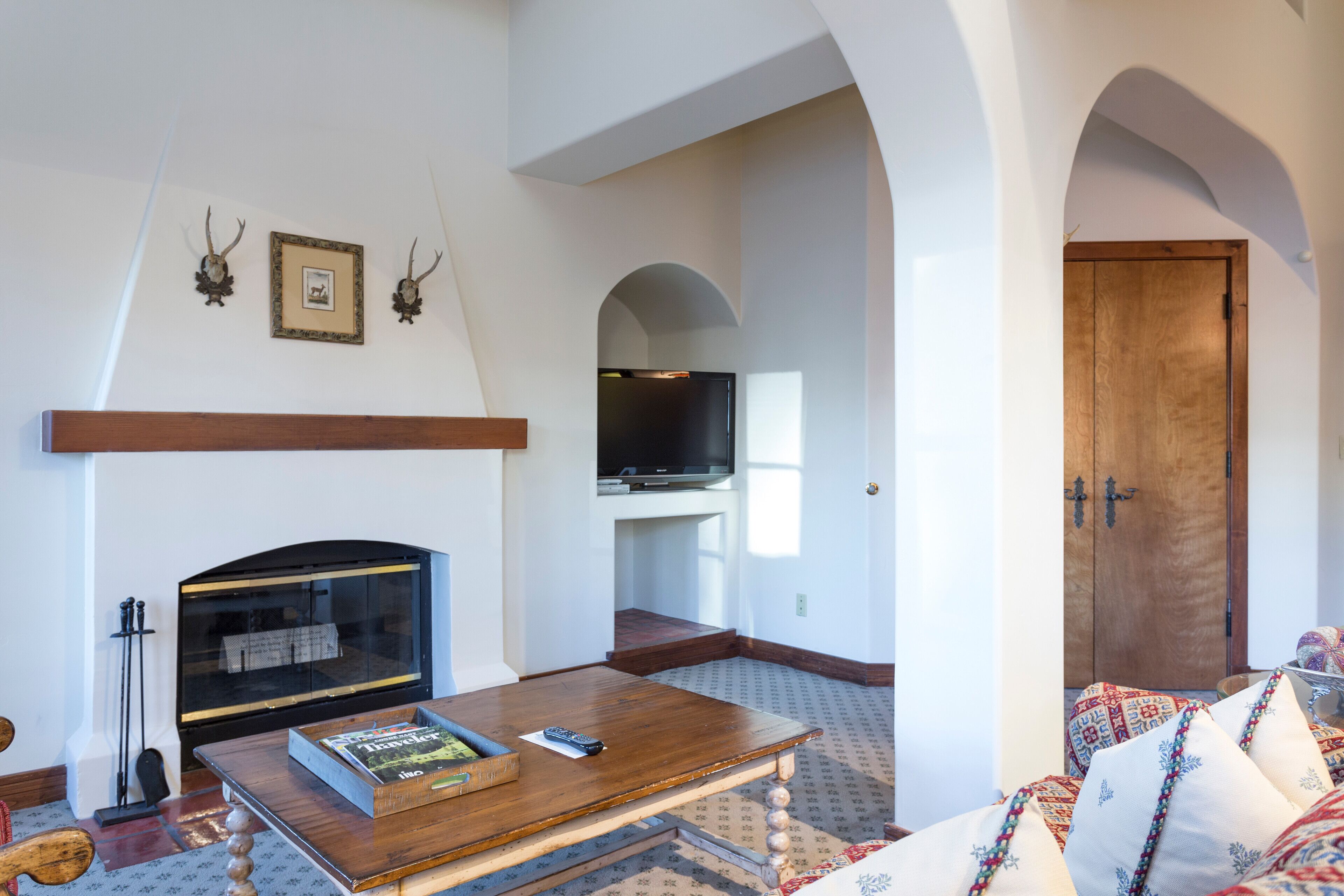 Una sala de estar con chimenea, un televisor montado en la pared y una puerta de madera.