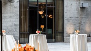 An outdoor dining area with tables set for a meal, featuring floral centerpieces and candles. - Goldener Hirsch, Auberge Collection (Park City)