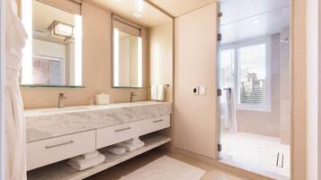 A modern bathroom with a marble vanity, a large mirror, and a walk-in shower.