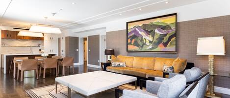 Uma sala de estar moderna com um sofá, uma mesa de centro e uma área de jantar com cadeiras.