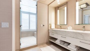 A modern bathroom with a glass-enclosed shower, a marble vanity, and a large mirror.