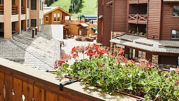 Un bâtiment en bois doté d’un balcon, entouré de verdure et situé dans un paysage vallonné.