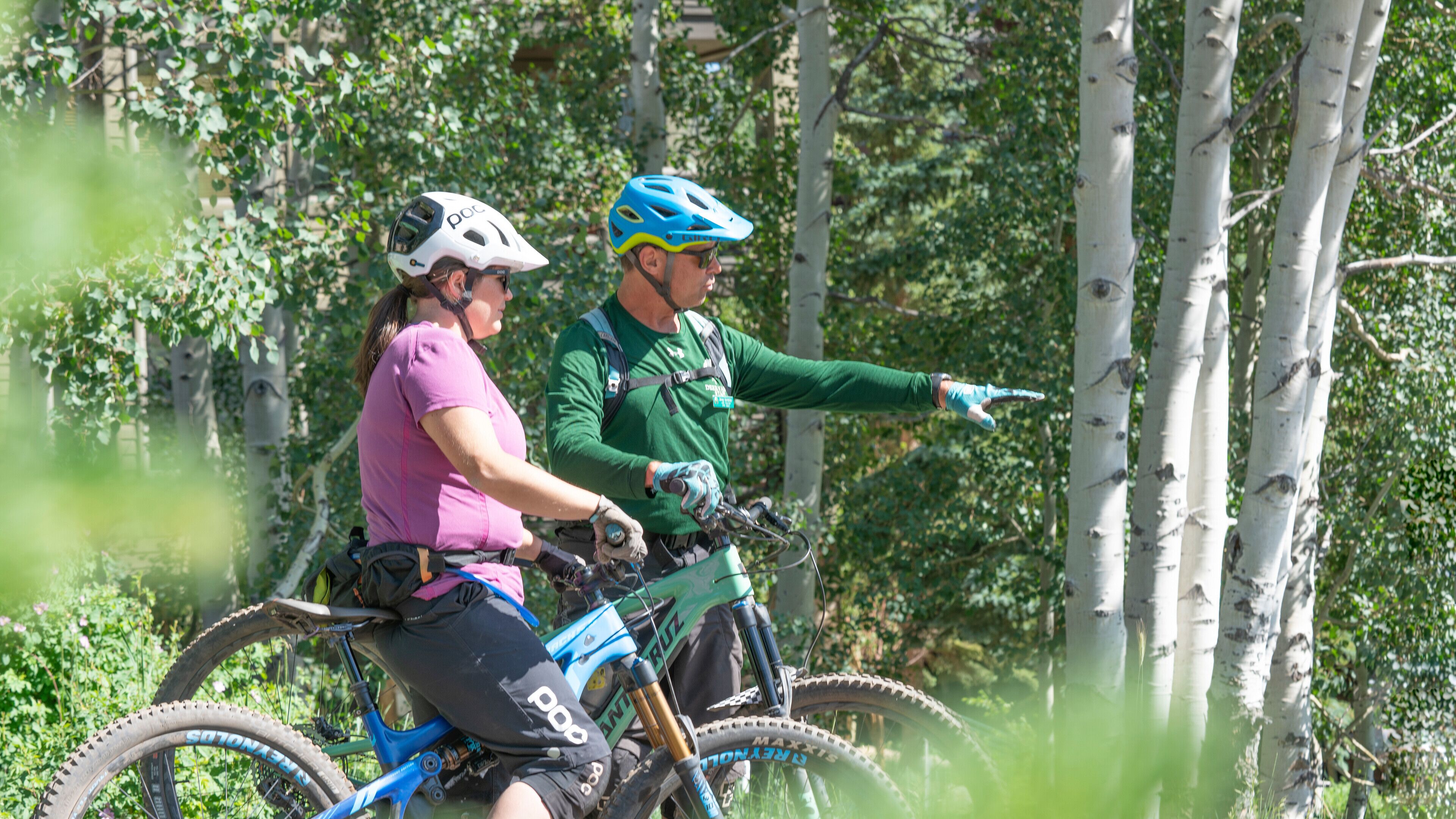 Two people on a mountain bike trail in a forested area.