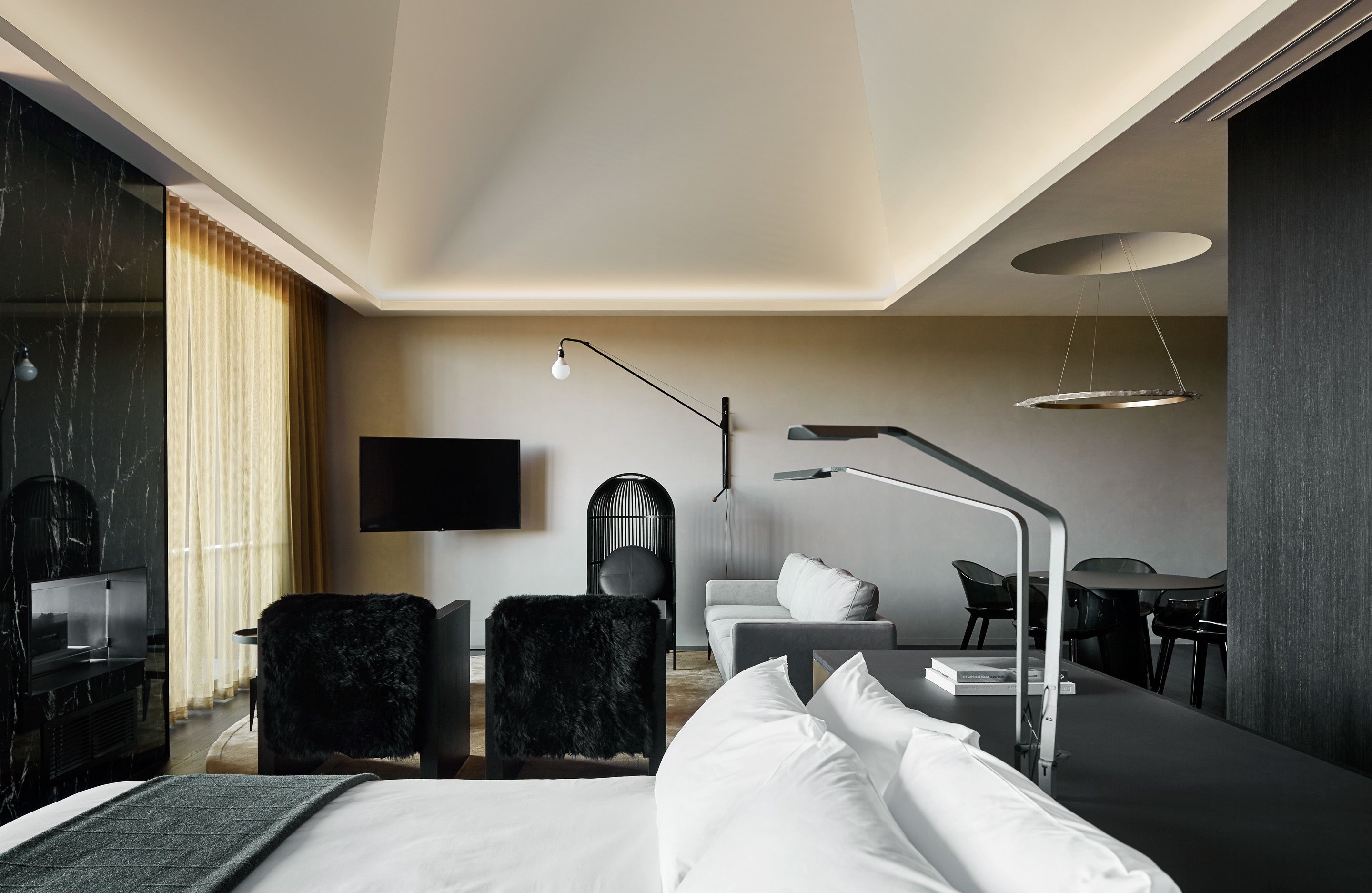 Una habitación de hotel moderna con una cama, un escritorio, una silla, un sofá y un televisor.