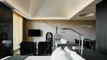 Una habitación de hotel moderna con una cama, un escritorio, una silla, un sofá y un televisor.