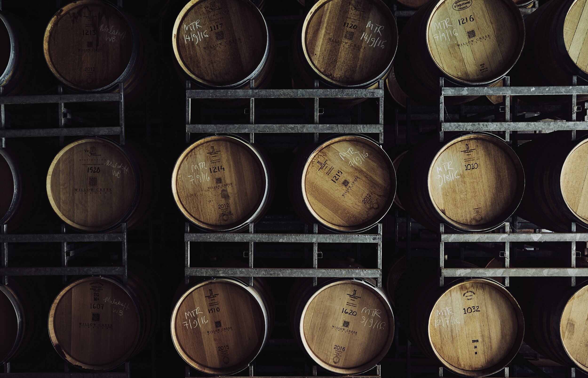 Wooden barrels stacked in rows on metal racks.