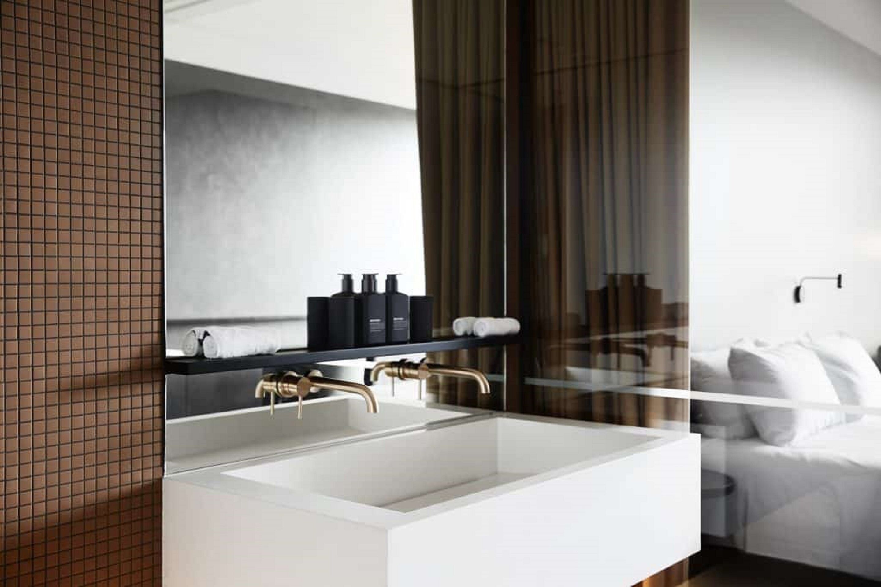 A modern bathroom with a large rectangular sink, a mirror, and a towel rack.