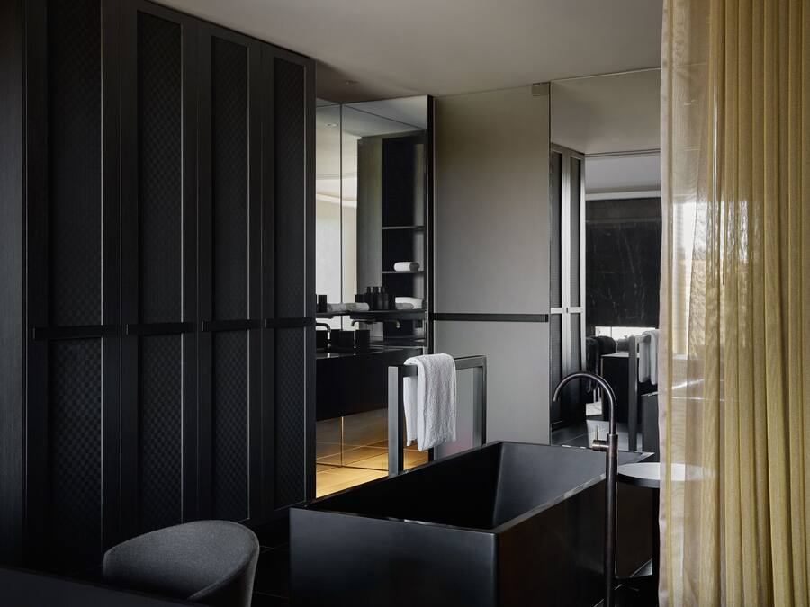 Un baño moderno con un espejo grande, un lavabo negro y una toalla colgada en la pared.