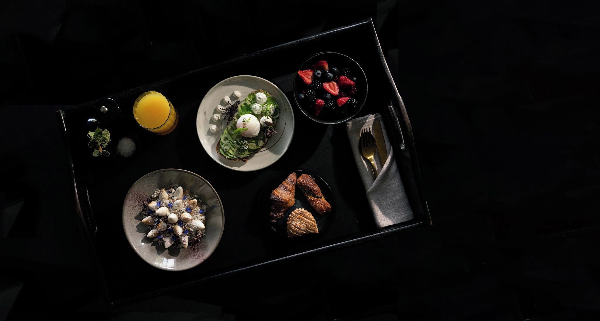 A tray with various food items including a salad, fruit, and pastries.