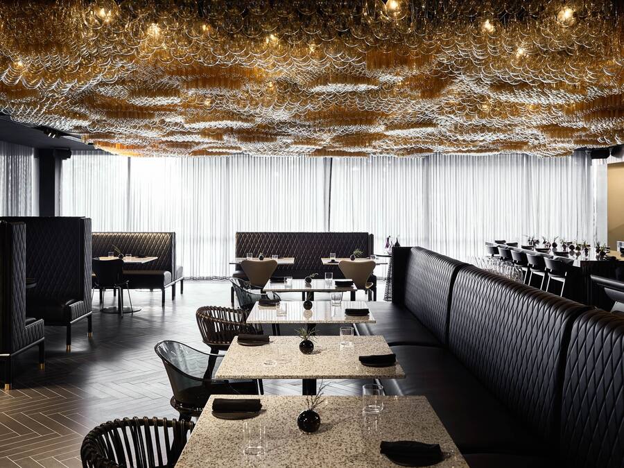 Un restaurante moderno con un diseño de techo original, una amplia zona de comedor y una barra.