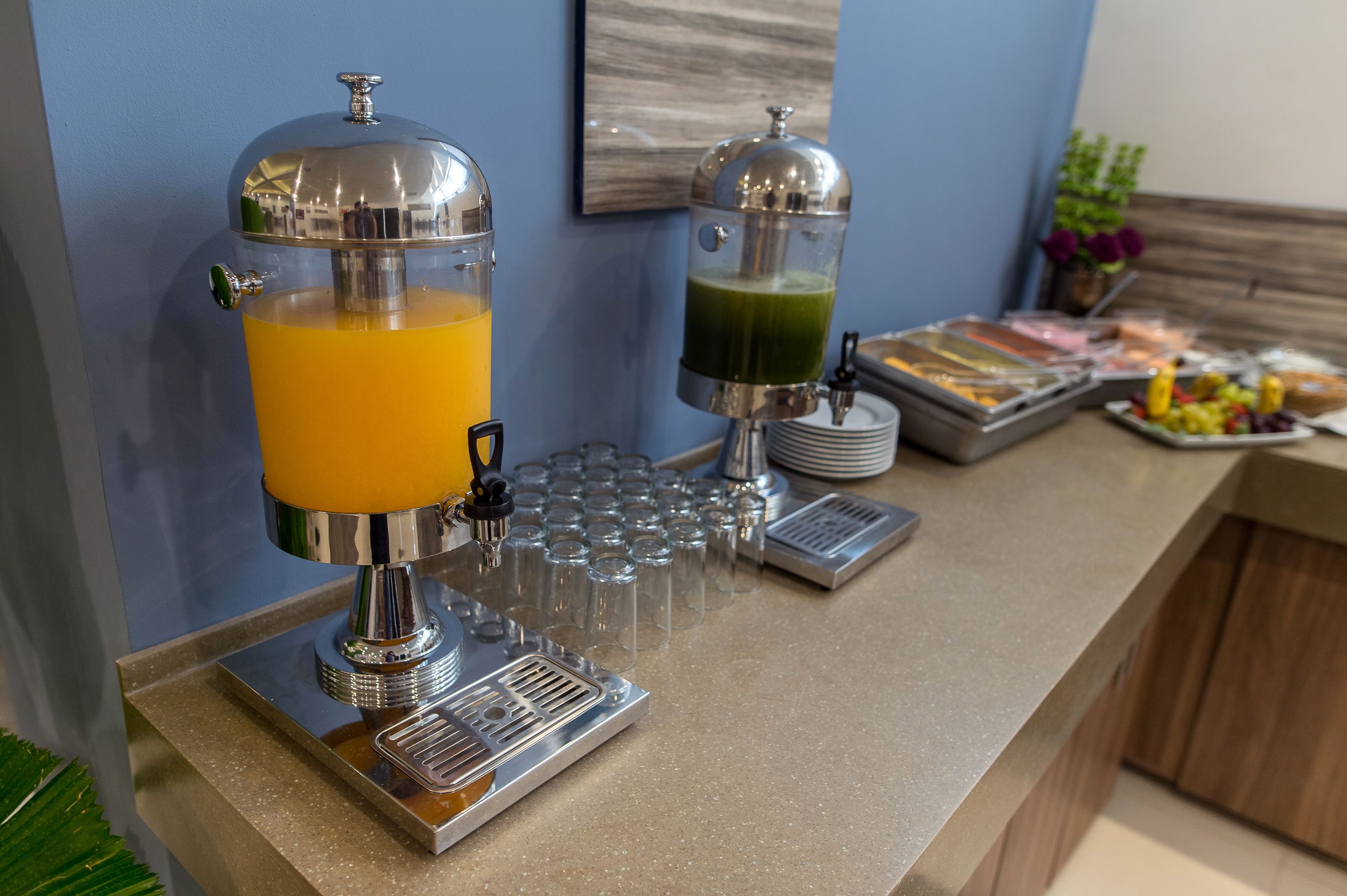 A breakfast bar with juice dispensers, a fruit tray, and a coffee station.