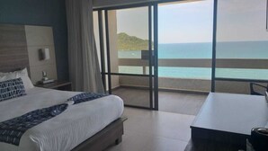 A bedroom with a large bed, a desk, and a view of the sea. - Ocean View Beach Hotel (Mazatlán)