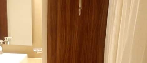 A bathroom with a wooden shower enclosure, a sink, and a mirror.