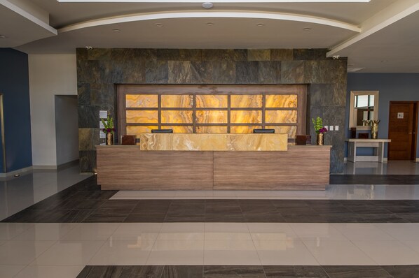 A reception desk with a marble back wall and a large window.