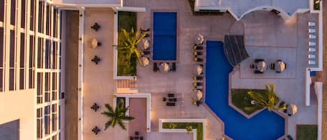 Vista aérea de un hotel con piscina, zonas de estar al aire libre y aparcamiento.
