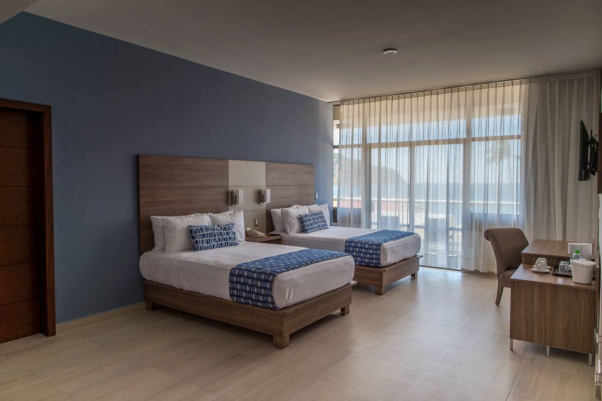 Una habitación de hotel con dos camas, un escritorio y una silla.