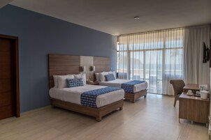 Habitación de hotel con dos camas, un escritorio y una silla.