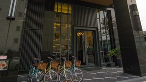 L'esterno del Watermark Hotel, con una facciata moderna, un ampio ingresso in vetro e tre biciclette parcheggiate davanti.