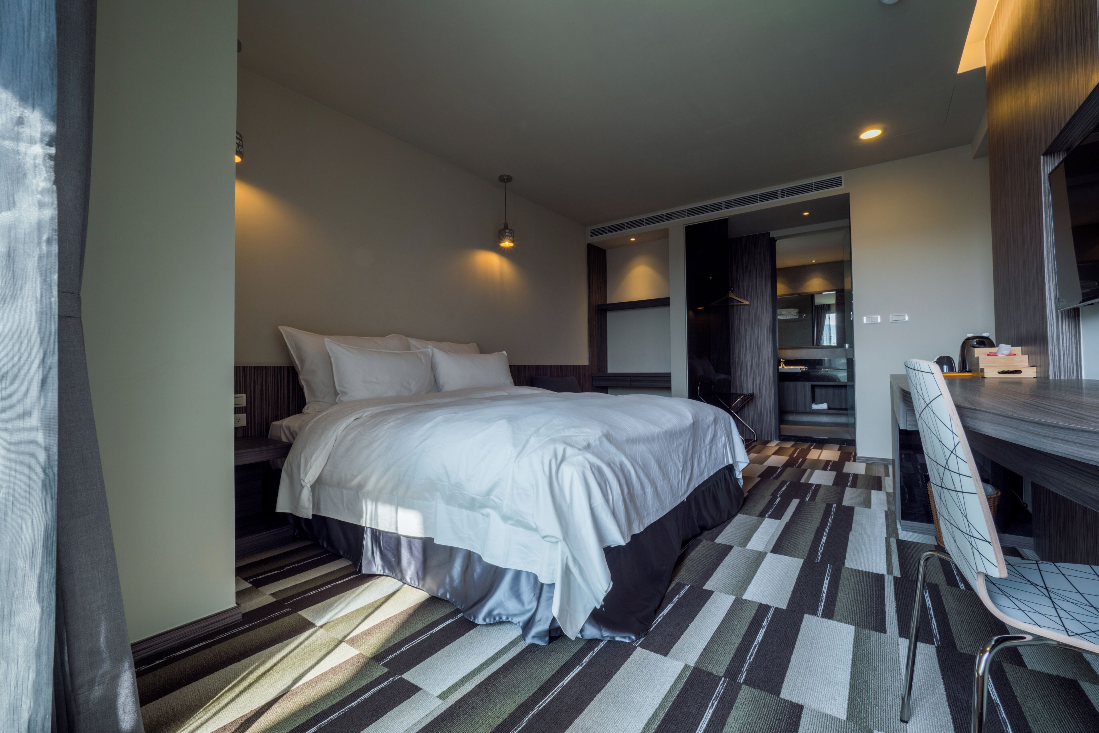 Una habitación de hotel moderna con una cama grande, un escritorio y vista al área de la cocina.