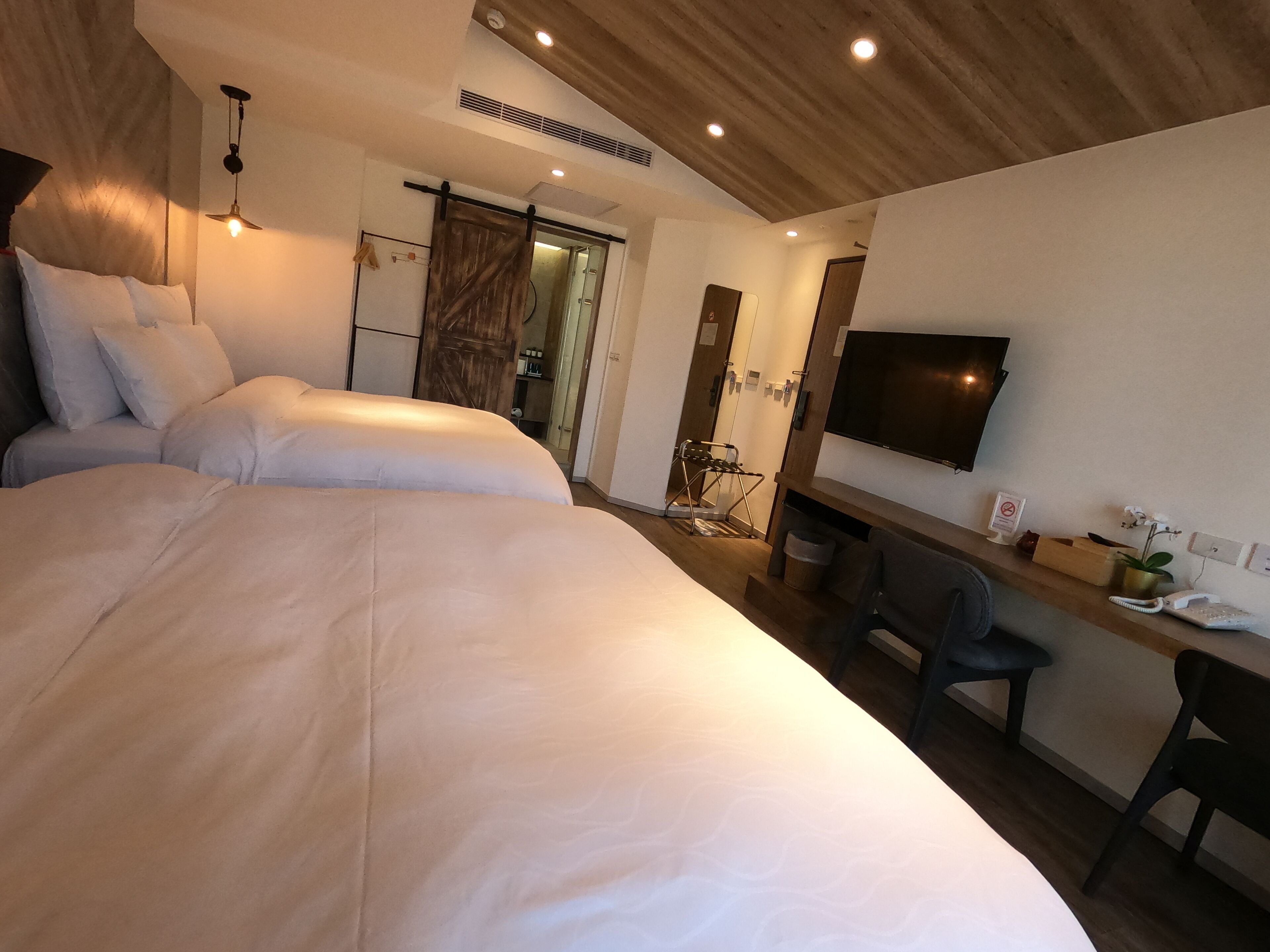 Una habitación de hotel moderna con una cama grande, un escritorio, una silla, un televisor y un armario.