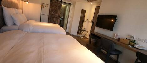 Una habitación de hotel moderna con una cama grande, un escritorio, una silla, un televisor y un armario.