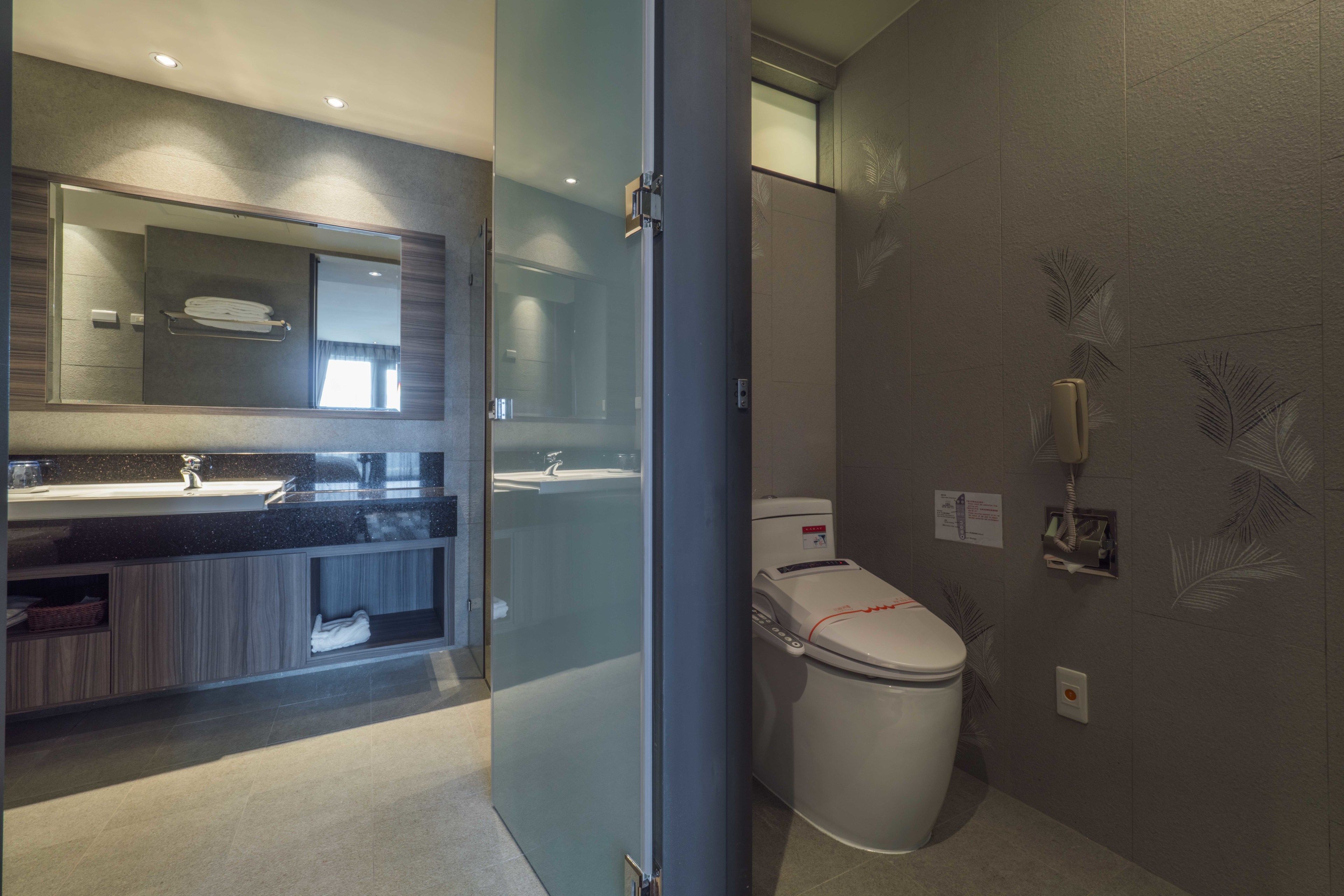 A modern bathroom with a glass partition, a sink, a toilet, and a shower area.