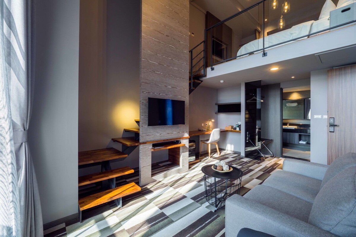 A modern interior with a staircase, a sofa, a dining area, and a kitchen.