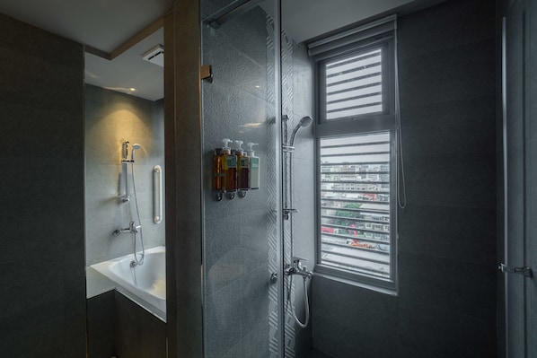 A modern bathroom with a glass-enclosed shower, a white sink, and a window with a city view. - Watermark Hotel Kaohsiung Station (Kaohsiung)