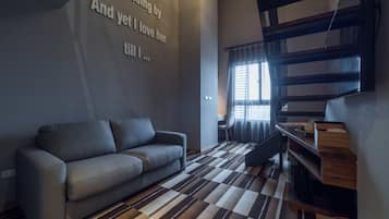 A modern living room with a sofa, a patterned rug, a wooden coffee table, and a staircase.