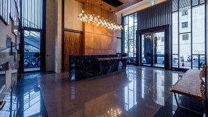 Una hall moderna con una reception in marmo, ampie finestre e un'originale lampada a sospensione.