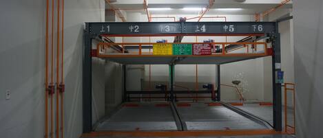 An indoor parking garage with numbered parking bays and orange safety railings.