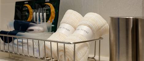 A metal rack with neatly folded towels and a metallic mug on a white surface.